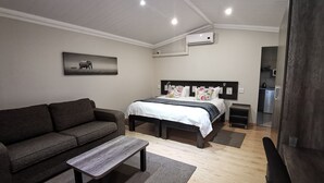 Une chambre à coucher moderne avec un lit, un canapé, une table basse et un tableau au mur.