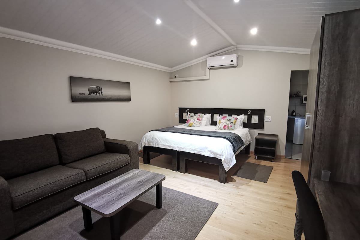A modern bedroom with a bed, a sofa, a coffee table, and a painting on the wall.