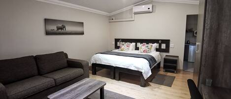 Une chambre à coucher moderne avec un lit, un canapé, une table basse et un tableau au mur.