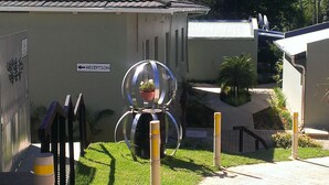 Un espace d’accueil avec un panneau indicateur, une sculpture sphérique et une plante en pot.
