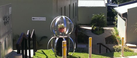 A reception area with a directional sign, a spherical sculpture, and a potted plant.