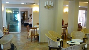 A hotel lobby with wicker chairs, a dining area, and a reception desk. - Jole (Cesenatico)