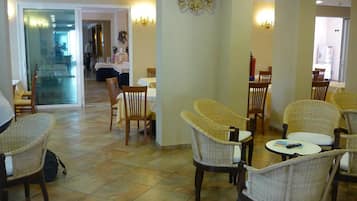 Un vestíbulo de hotel con sillas de mimbre, un comedor y una recepción.