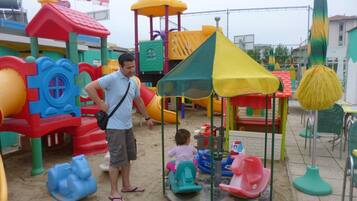 Un parque infantil con diversas estructuras de juego, incluyendo toboganes y una zona de escalada.