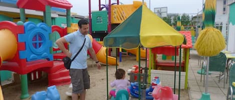 Un parque infantil con diversas estructuras de juego, incluyendo toboganes y una zona de escalada.