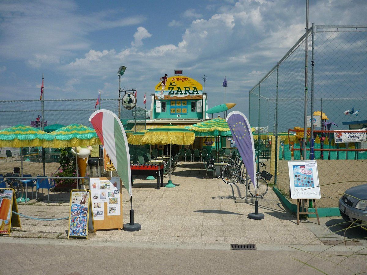 Un restaurante frente a la playa con terraza y zona delimitada por una valla.