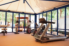 A covered outdoor gym area with exercise equipment, including treadmills and a stationary bike, under a large canopy. - Camping Village Laguna Blu (Alghero)