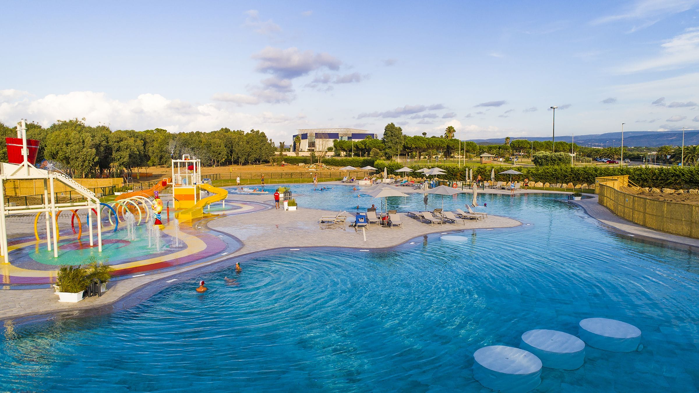 Un parco acquatico con una grande piscina, scivoli e un'area giochi.