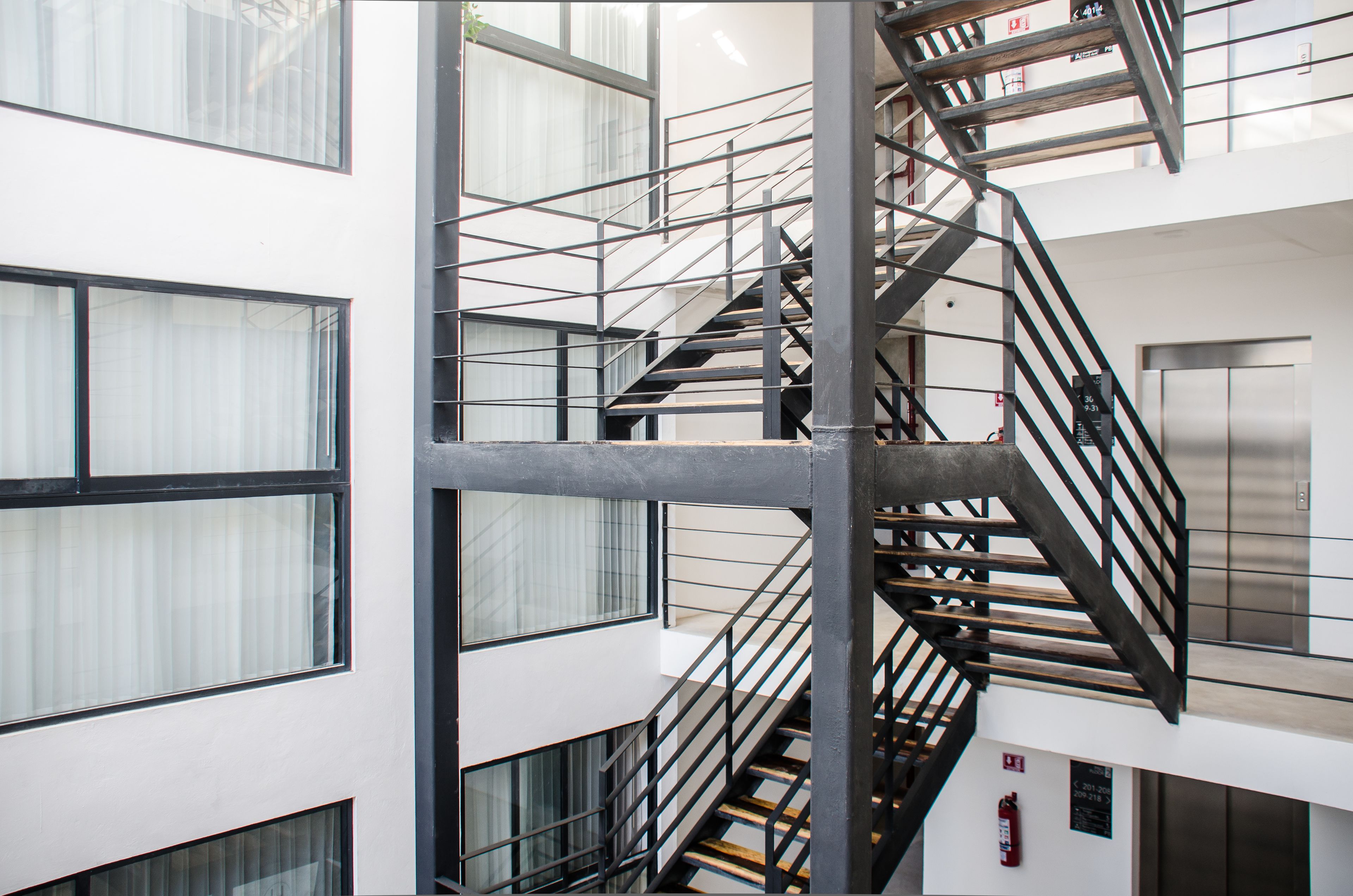 A multi-level interior with a central staircase, large windows, and an elevator.