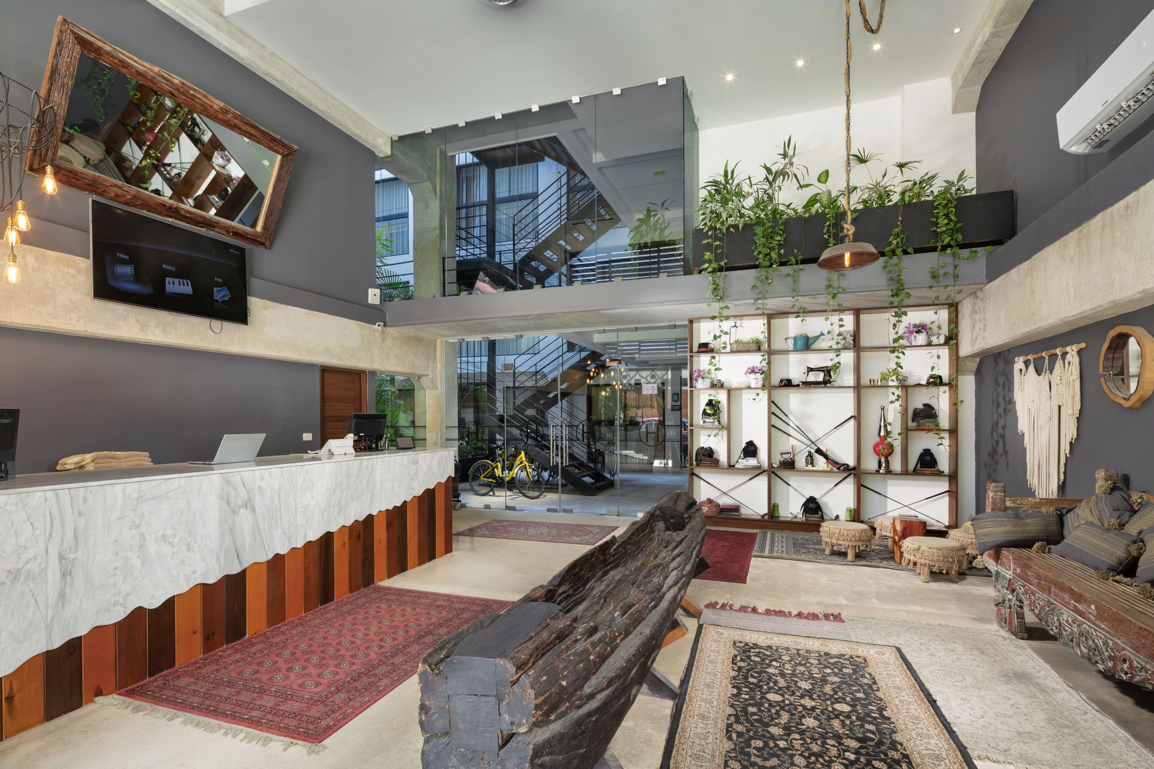 Un hall amplio con mostrador de recepción, zona de estar, escalera y varios objetos decorativos.