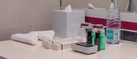 A bathroom counter with a tissue box, a bottle of water, a bottle of lotion, and a towel.