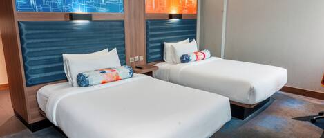 Zwei Einzelbetten mit Kopfteilen, weiße Bettwäsche und je ein Stadtbild über jedem Bett.