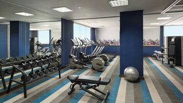 A gym with treadmills, elliptical machines, dumbbells, and a bench.