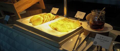 A breakfast buffet with pancakes, waffles, and maple syrup.