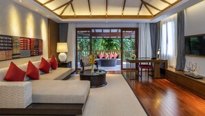 Un salón moderno con un sofá, una mesa de centro y un televisor. Hay un balcón con vistas a zonas verdes.
