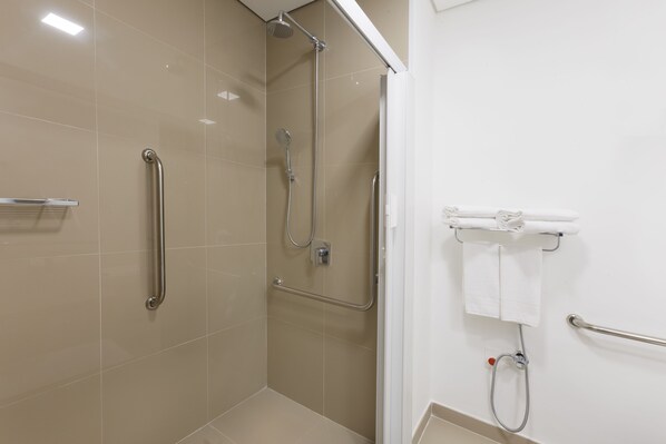A modern bathroom with a shower area, grab bars, and a towel rack. - Ramada Campinas Viracopos (Campinas)