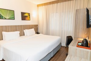 A hotel room with a large bed, a desk with a telephone, and a television on the wall. - Ramada Campinas Viracopos (Campinas)