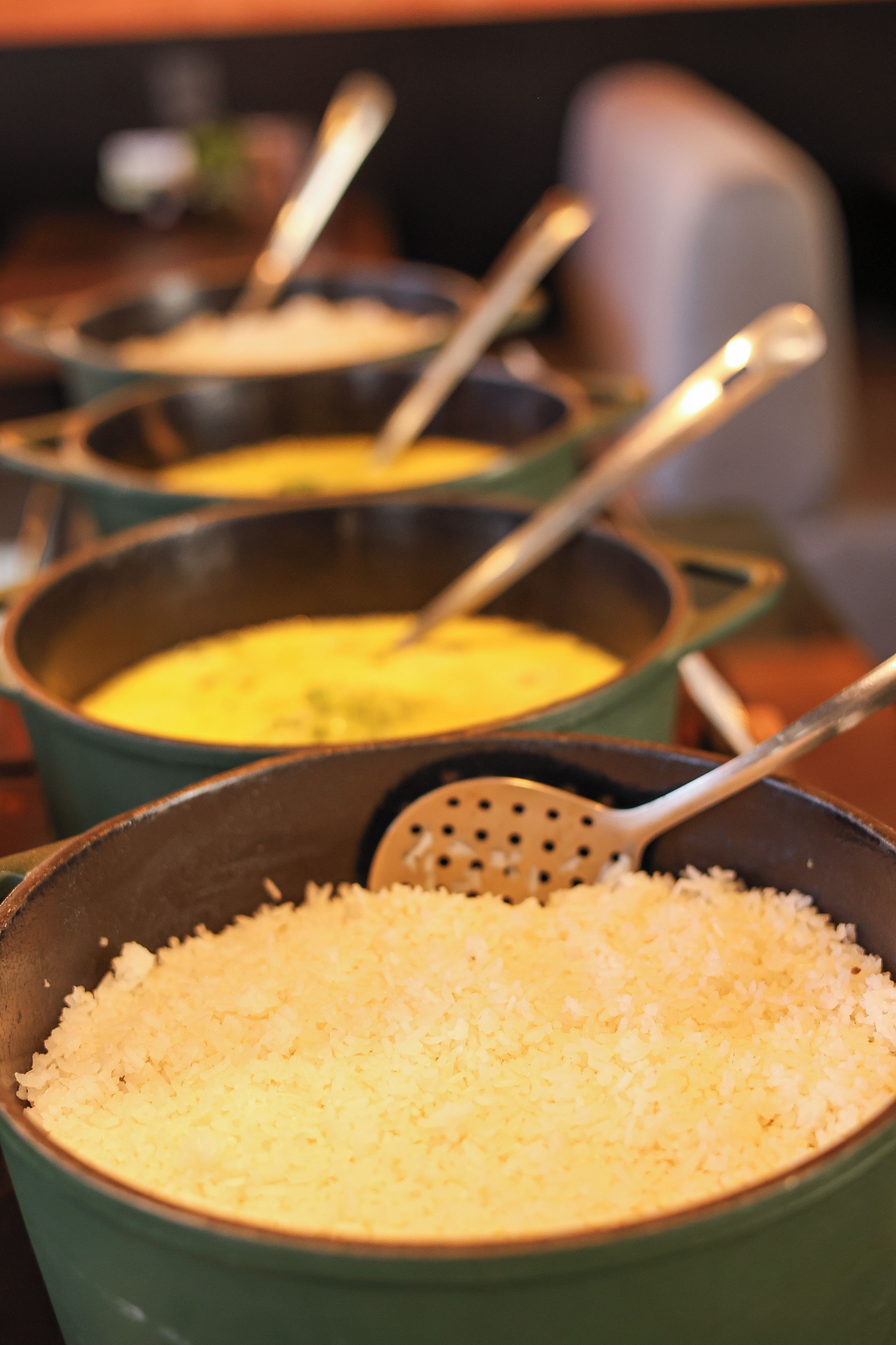 A series of pots with a yellow substance, possibly food, and a bowl of rice.
