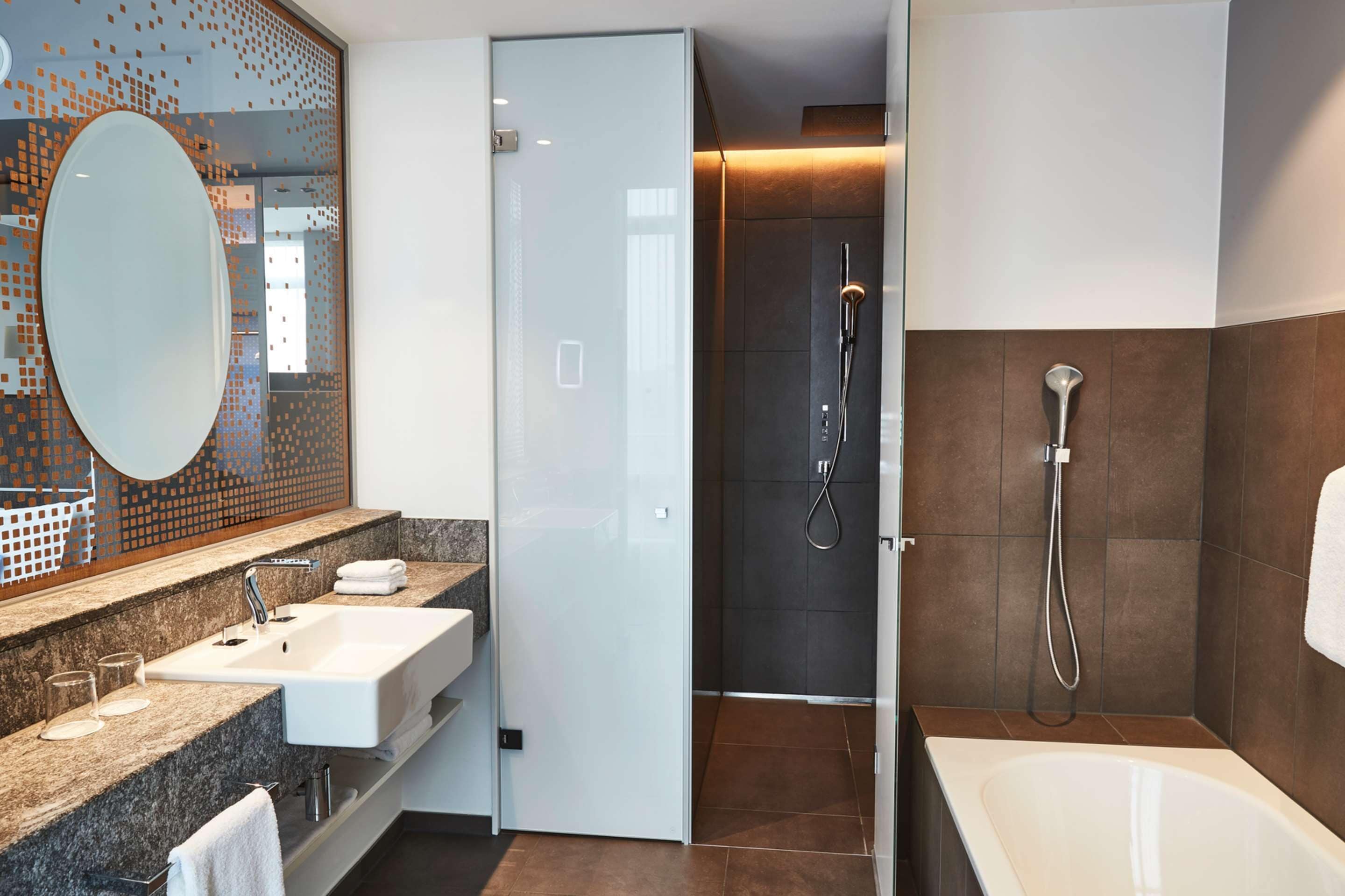 Un baño moderno con cabina de ducha de vidrio, una bañera independiente y un lavabo con un espejo grande y varios lavamanos.