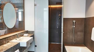 Un baño moderno con cabina de ducha de vidrio, una bañera independiente y un lavabo con un espejo grande y varios lavamanos.