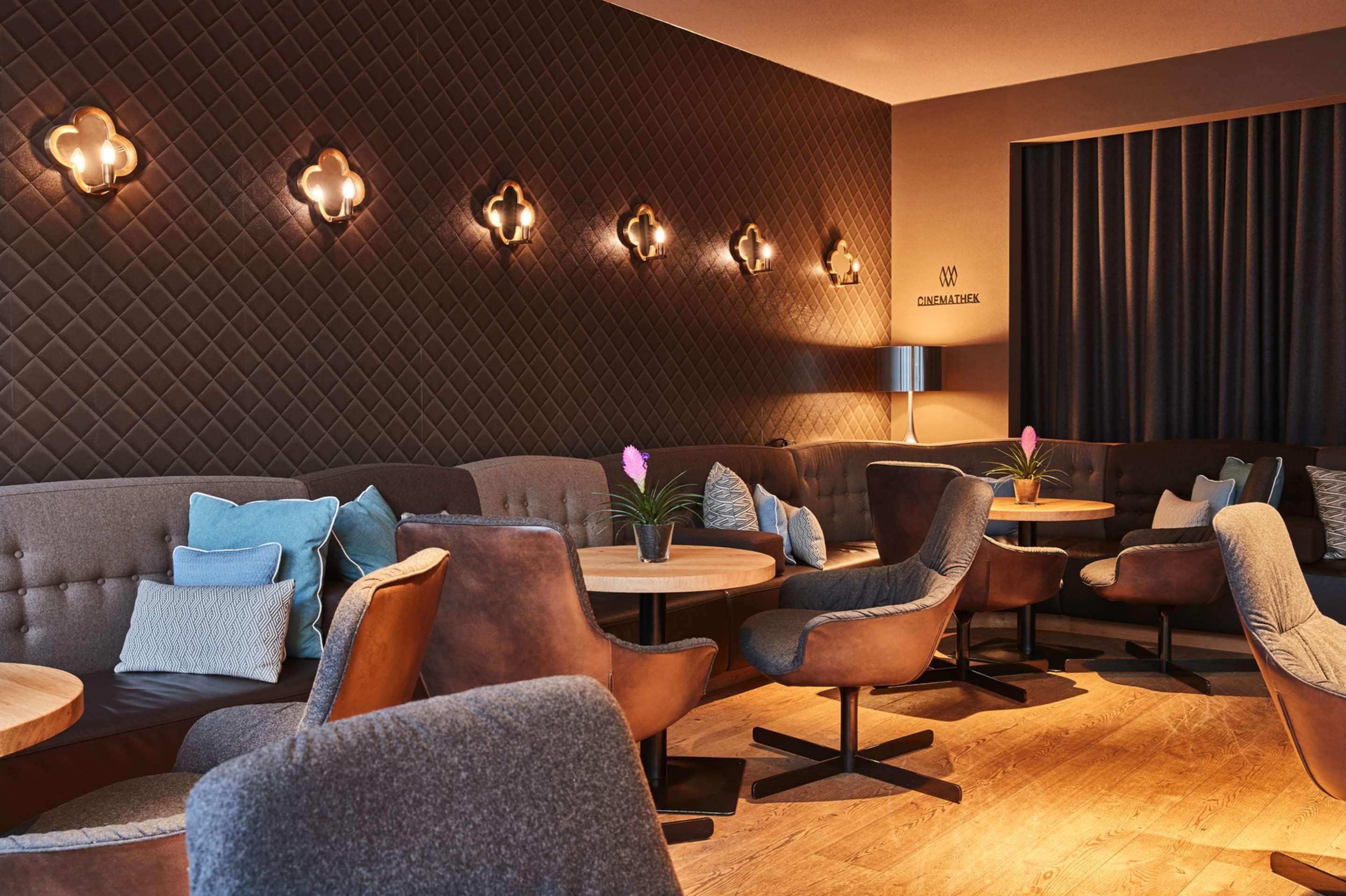 A modern lounge area with a quilted wall, round tables, and comfortable seating.