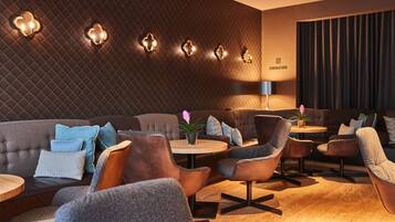 A modern lounge area with a quilted wall, round tables, and comfortable seating.