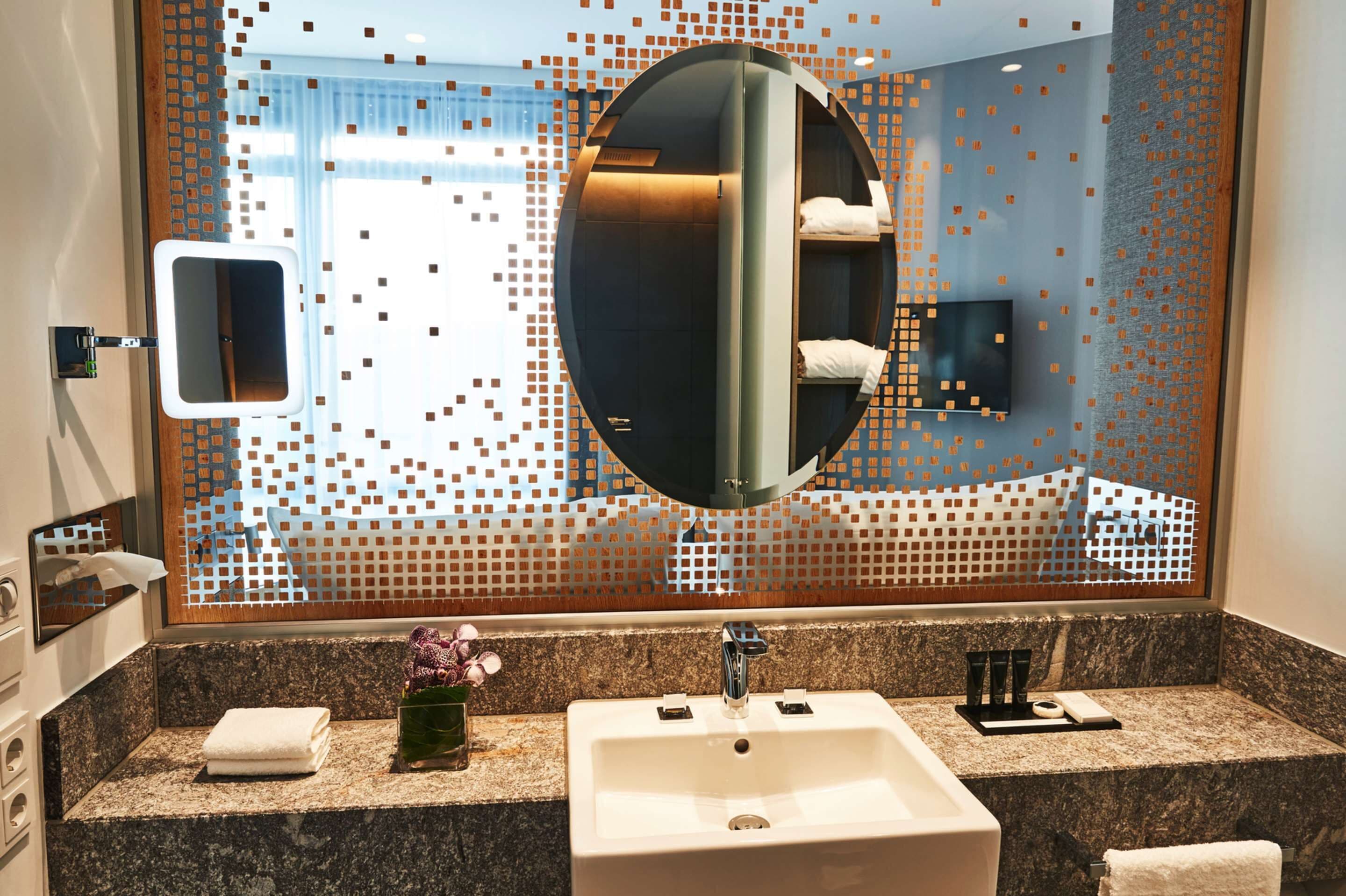A modern bathroom with a large mirror, a sink, and a vanity.