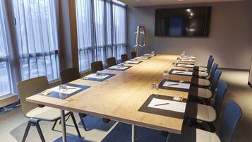 A conference room with a long table, chairs, and a TV screen on the wall.