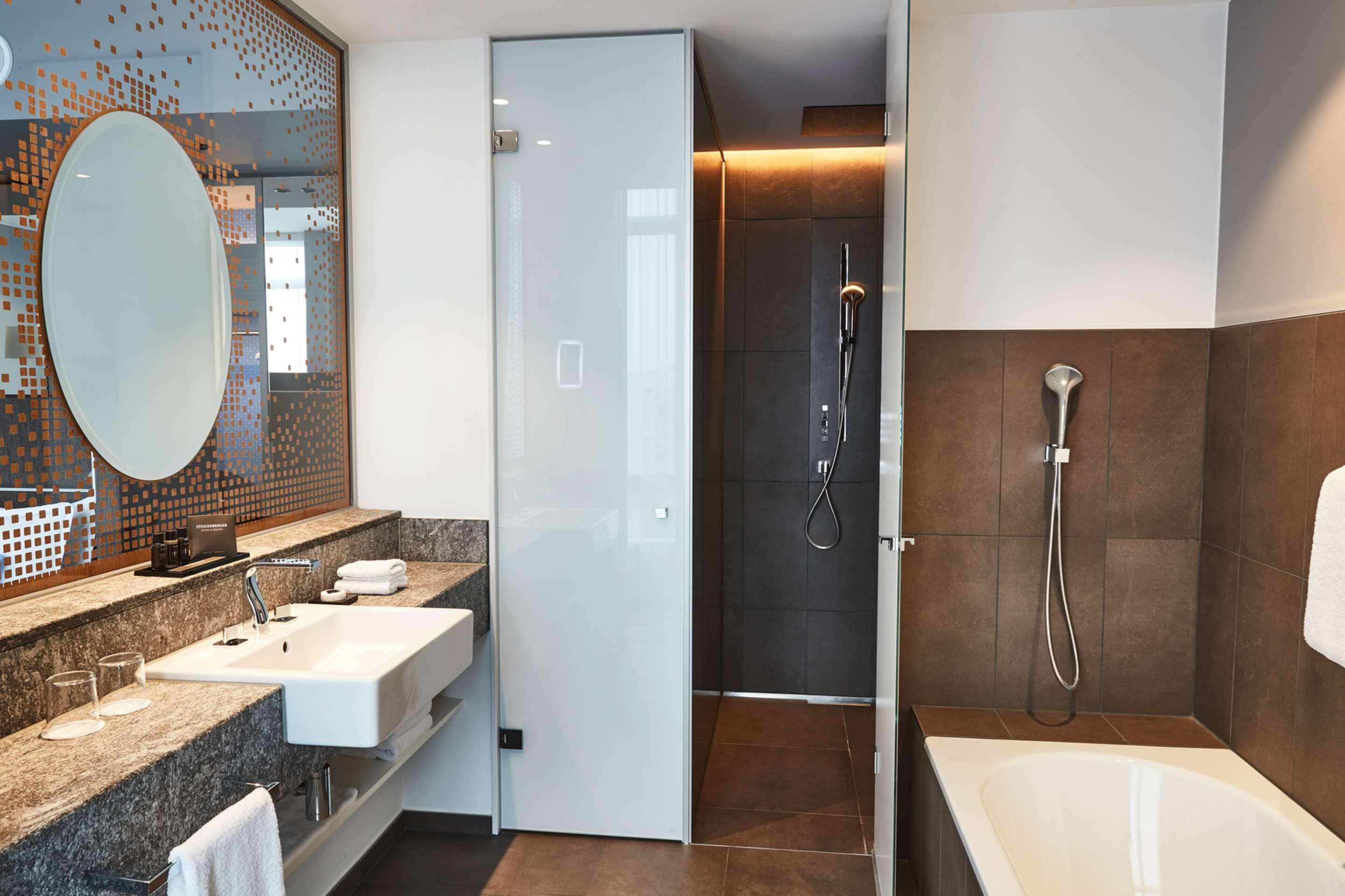 A modern bathroom with a large mirror, a sink, a shower, and a bathtub.