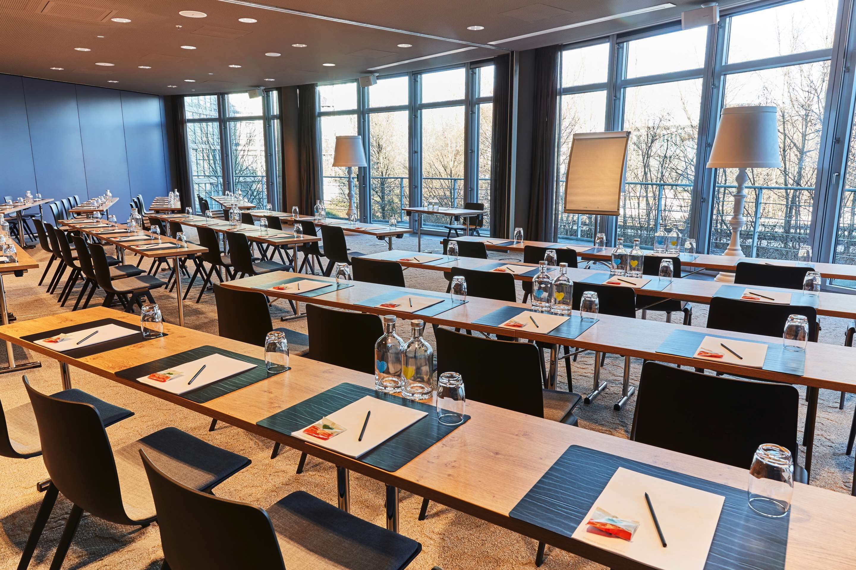 Ein Konferenzraum mit langen Tischen, Stühlen und großen Fenstern.