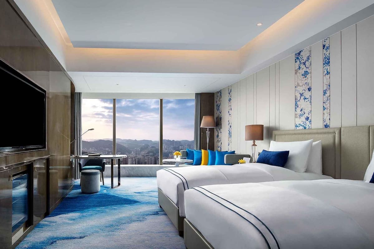 Une chambre d’hôtel avec un grand lit, une télévision, un bureau et une vue sur la ville.