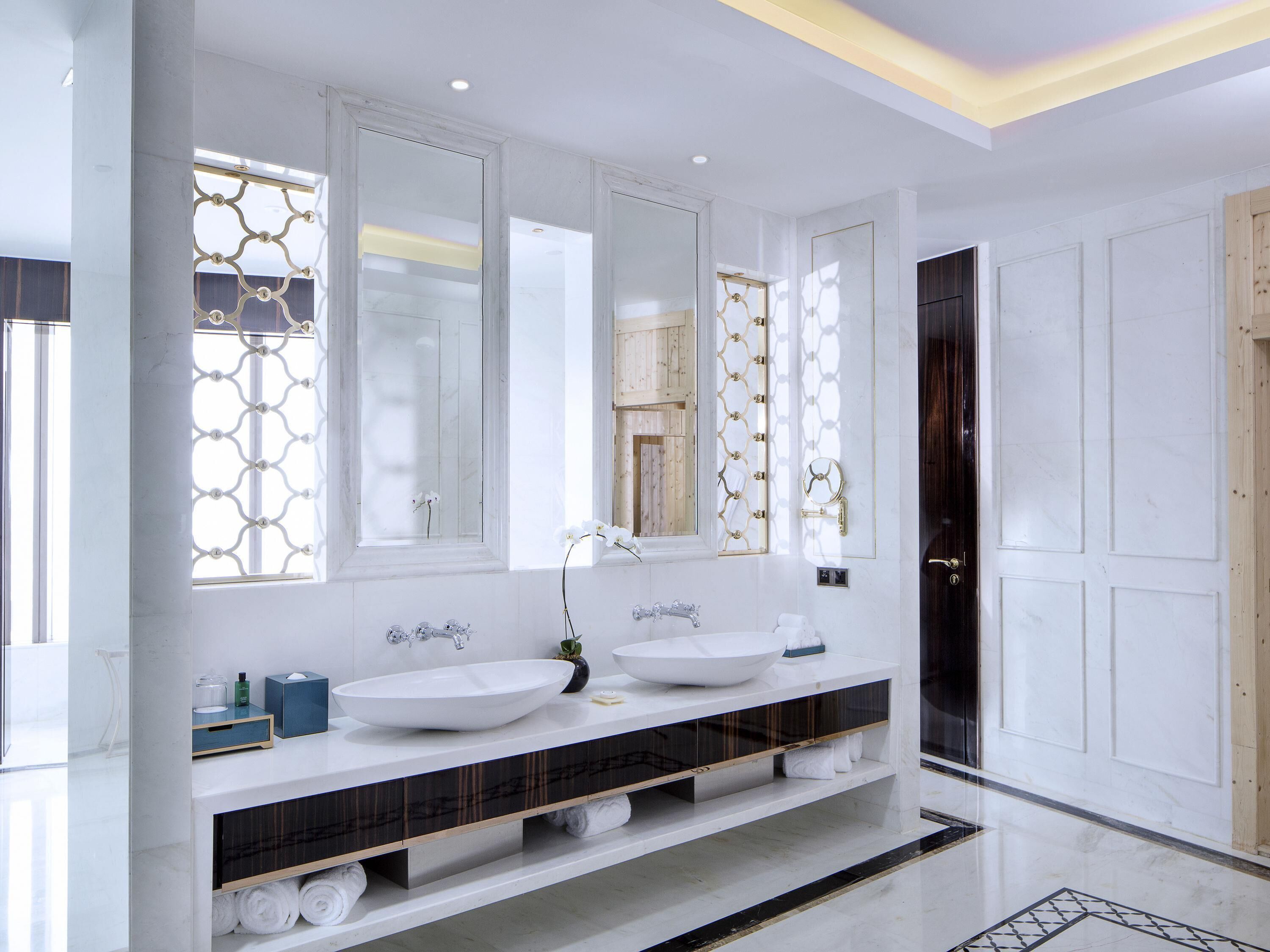 A modern bathroom with two sinks, a vanity, and a large mirror.