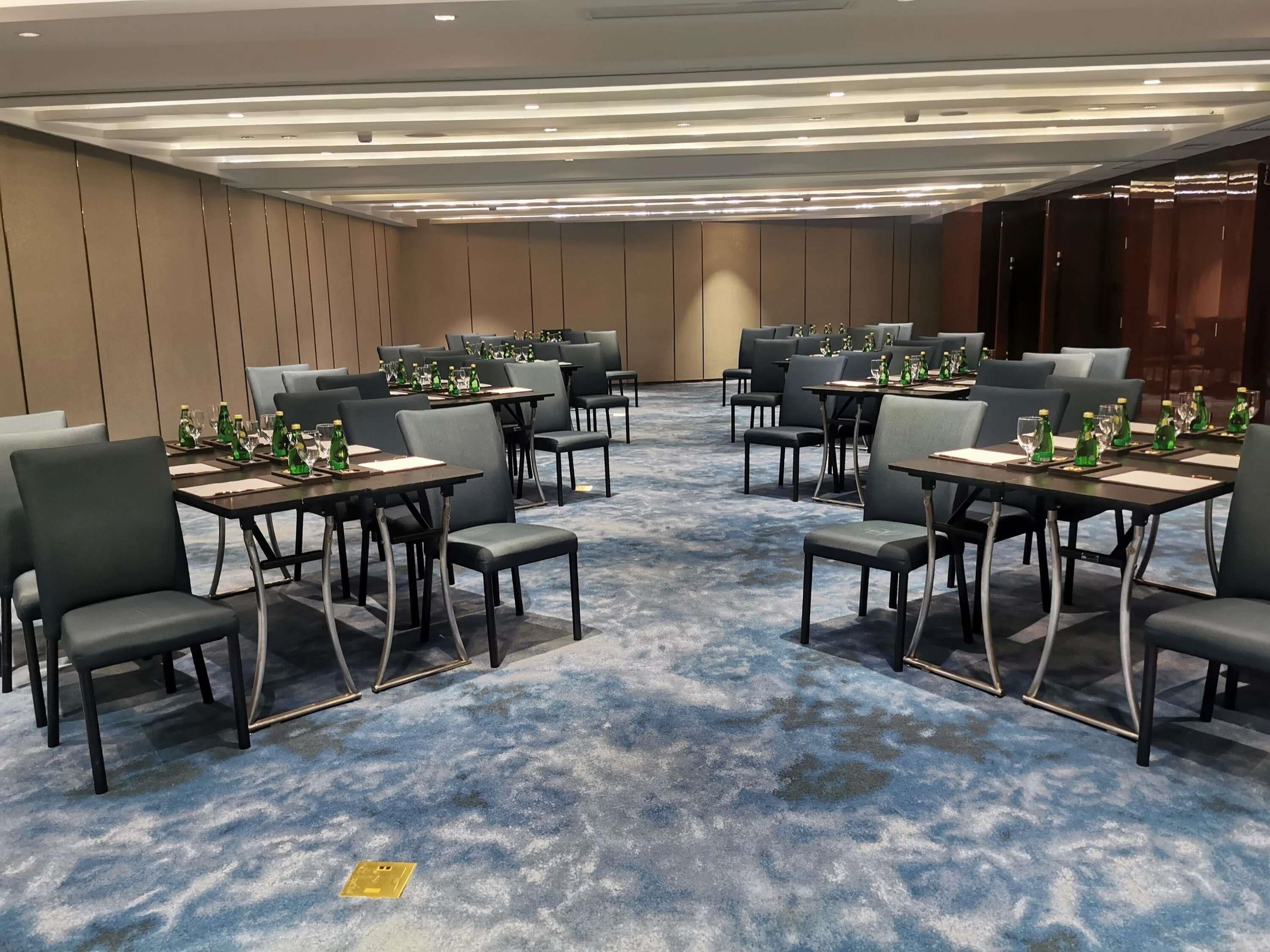 A conference room with tables set for meetings, equipped with chairs and water bottles.