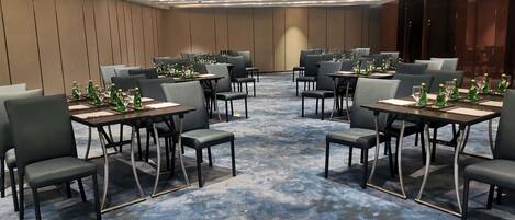 A conference room with tables set for meetings, equipped with chairs and water bottles.