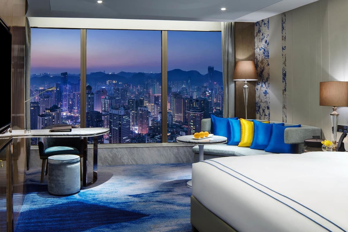 Habitació d'hotel amb vista a la ciutat, un llit, una taula i una cadira.
