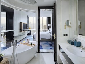 A modern hotel bathroom with a bathtub, a large mirror, and a sink.