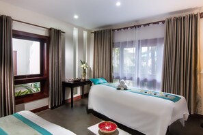 Una habitación de hotel con una cama grande, una mesita con un florero y una ventana con cortinas.