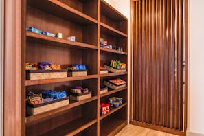 A wooden pantry with multiple shelves containing various food items and storage bins. - Holiday Inn Express & Suites Tampa North - Wesley Chapel by IHG (Wesley Chapel)