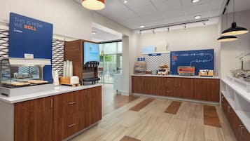 A modern cafe interior with a counter, a coffee machine, and a sign indicating a bakery section.