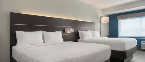 A hotel room with two beds, a large window, and a modern design.