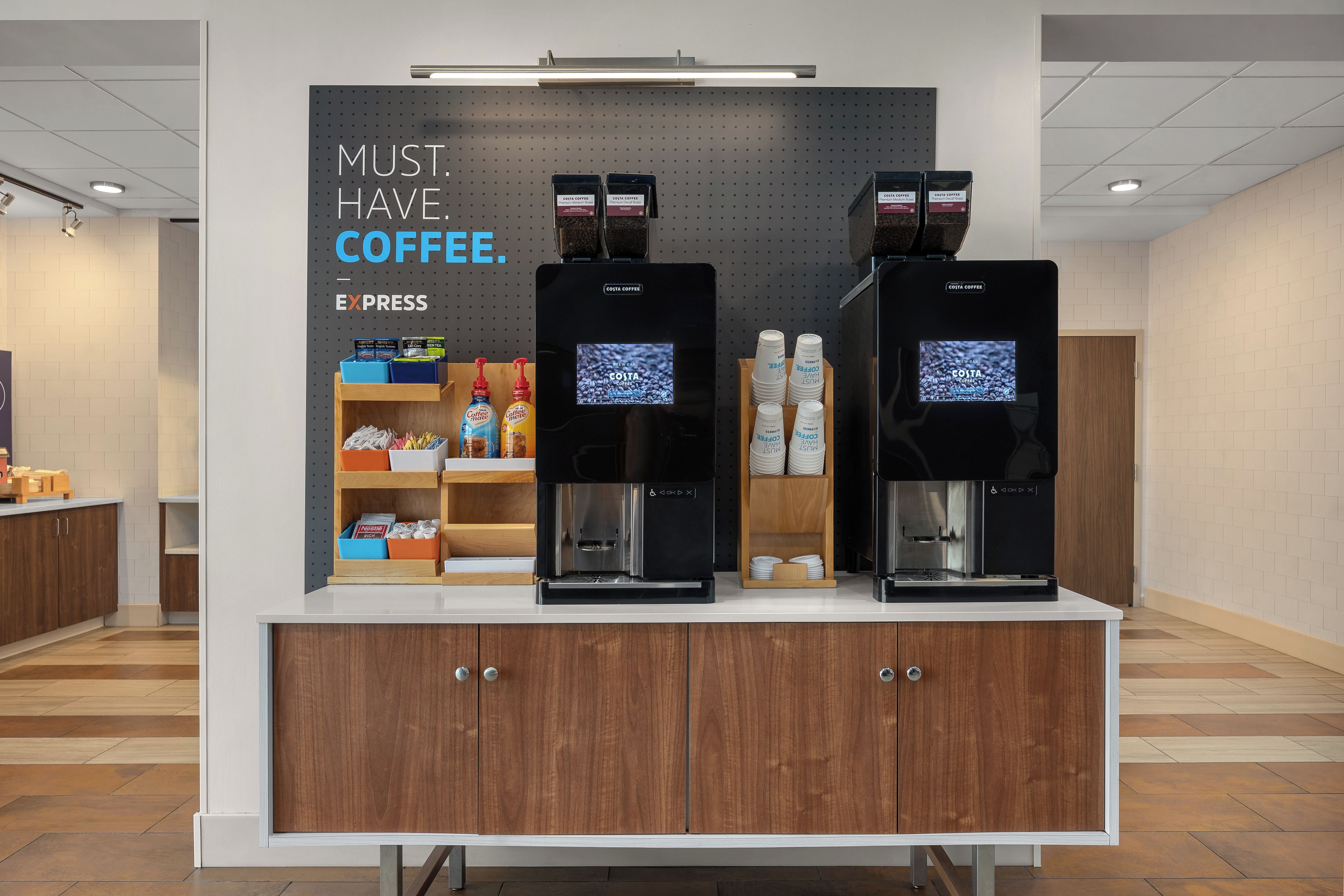 Una estación de café con dos máquinas de espresso, un letrero que dice 'MUST HAVE COFFEE' y diversos productos de café.
