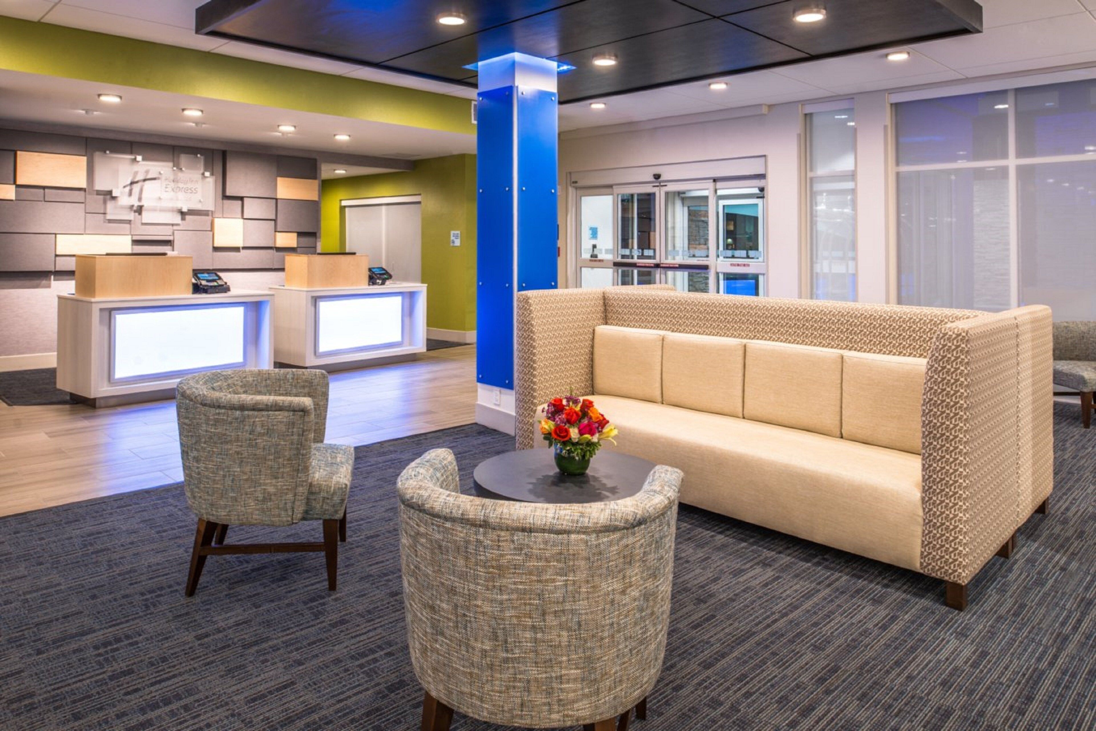 A reception area with a reception desk, two armchairs, a sofa, and a vase of flowers.