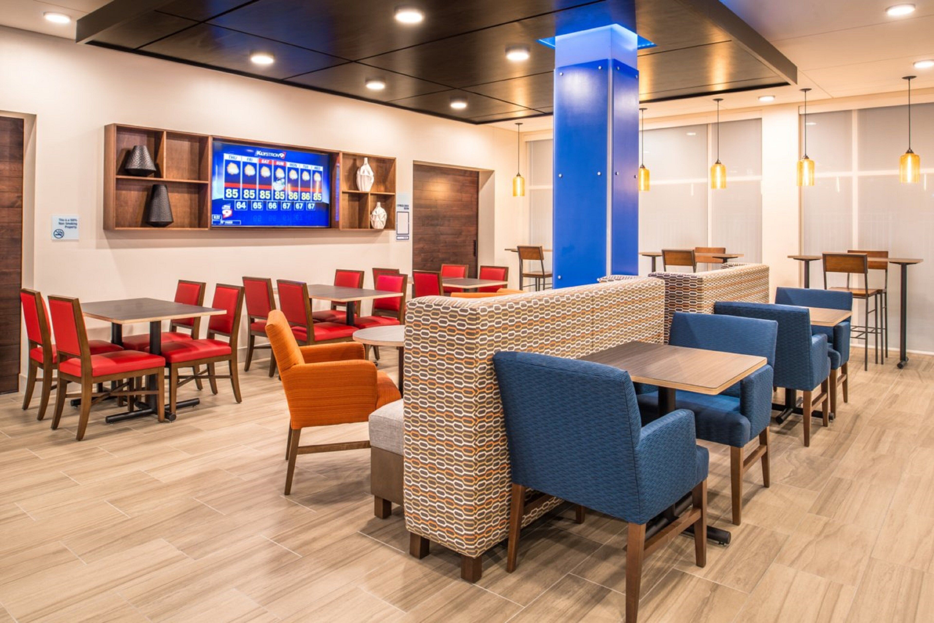 Un interior de restaurante moderno con diversas opciones de asientos, incluyendo cabinas y mesas, un menú digital y luminarias colgantes.