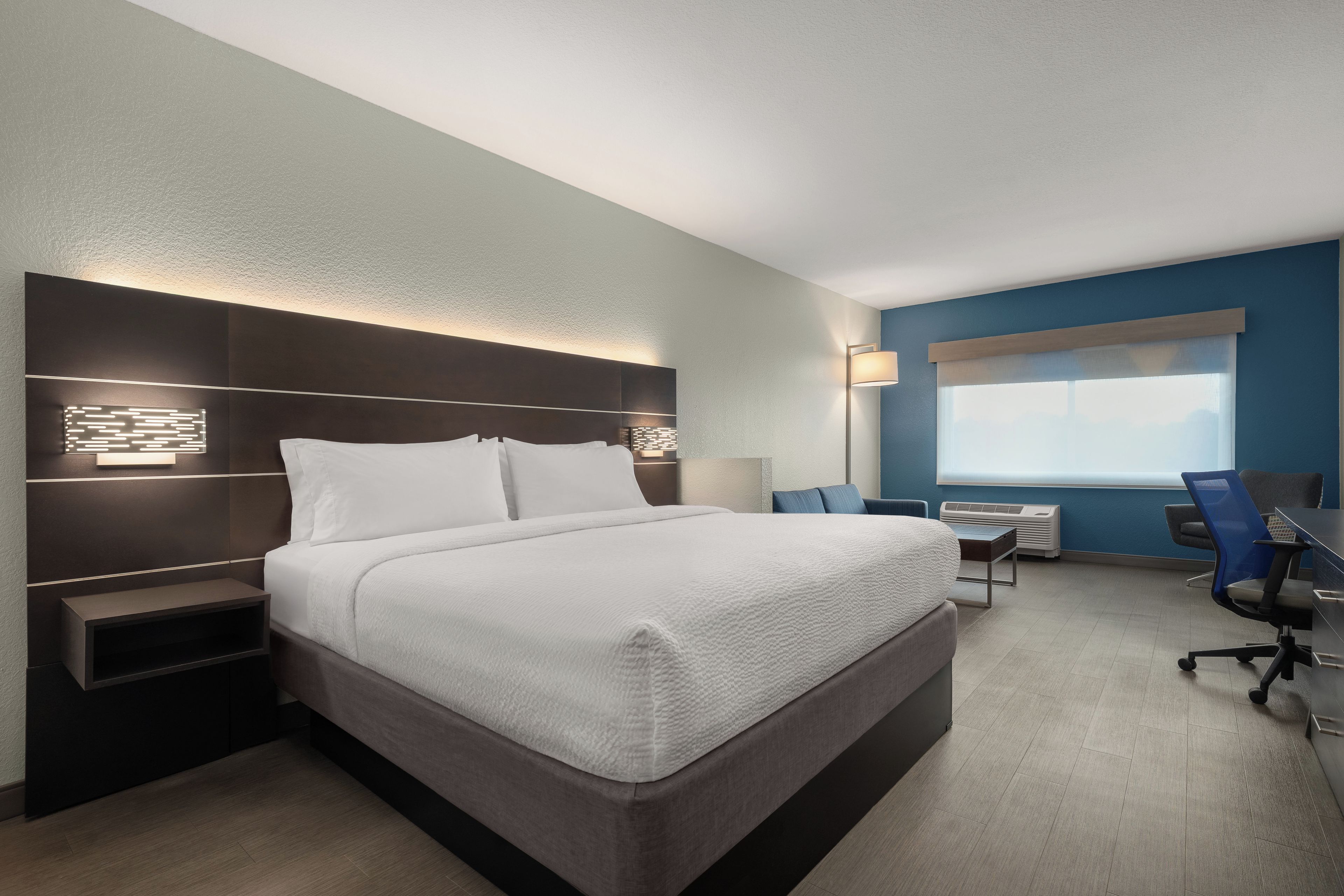 A modern hotel room with a large bed, bedside tables, a desk, and a chair.