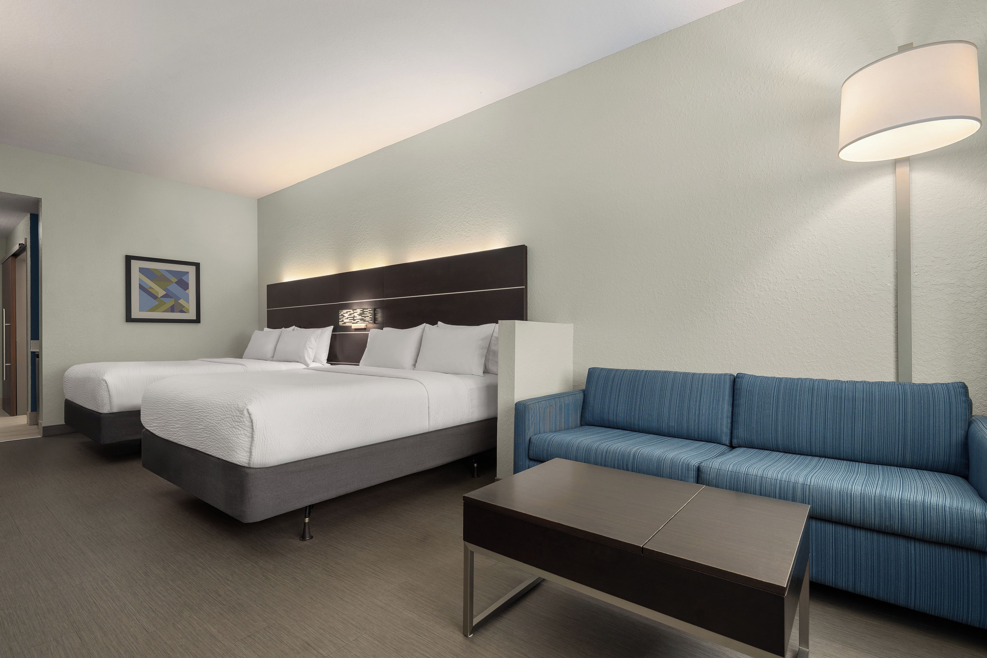 Ein Hotelzimmer mit einem Bett, einer Couch, einem Couchtisch und einer Wandlampe.