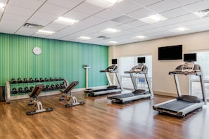 A gym with treadmills, dumbbells, and exercise equipment.