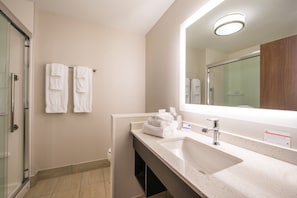 A modern bathroom with a large sink, a mirror, and two white towels hanging on the wall.