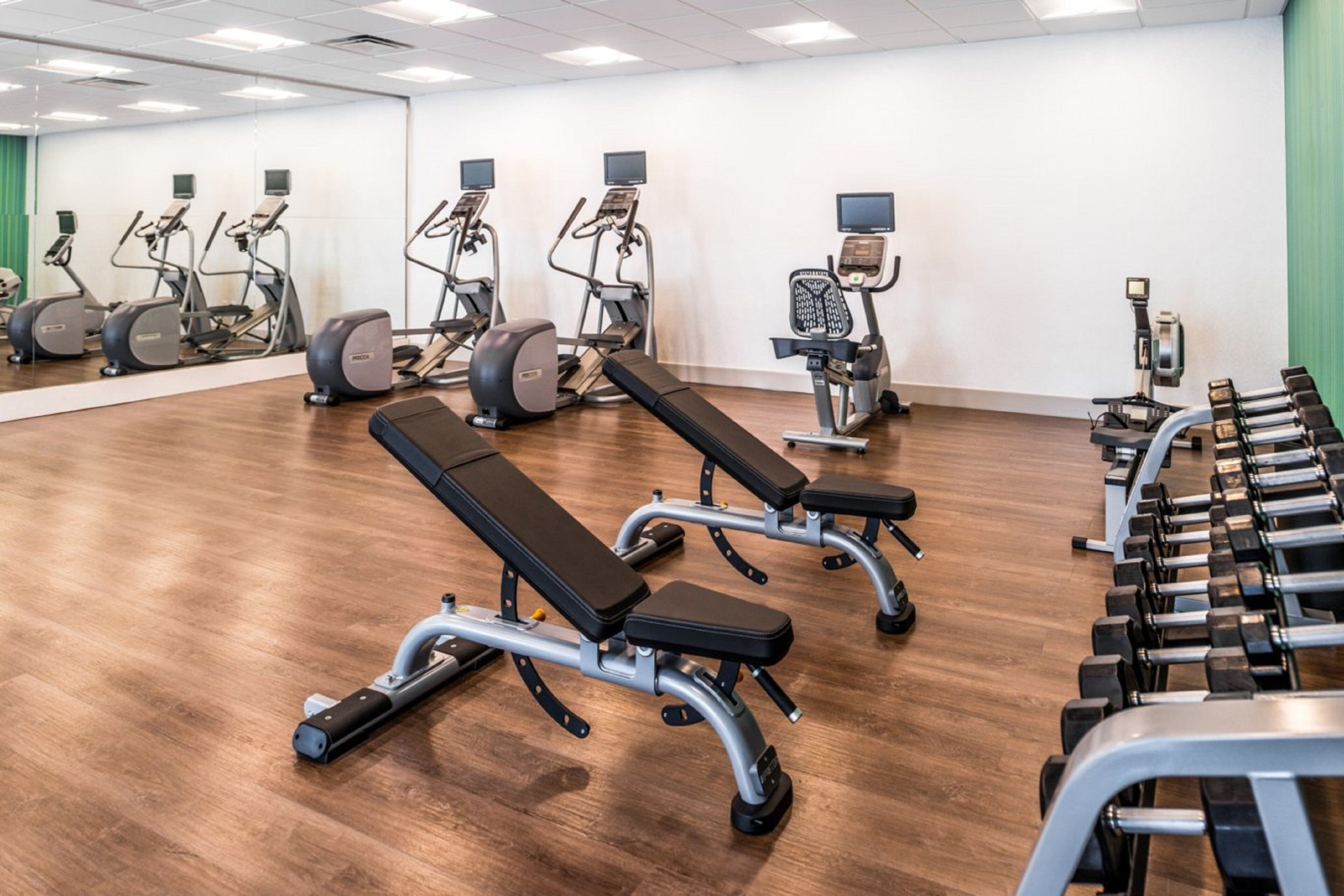 A gym with exercise equipment including treadmills, elliptical machines, and weight benches.