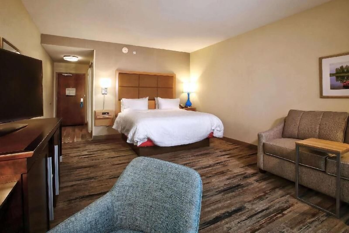 A hotel room with a bed, a sofa, a TV, and a desk.
