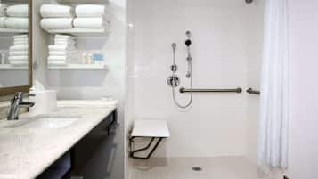 Un baño moderno con ducha, lavamanos y toallero.